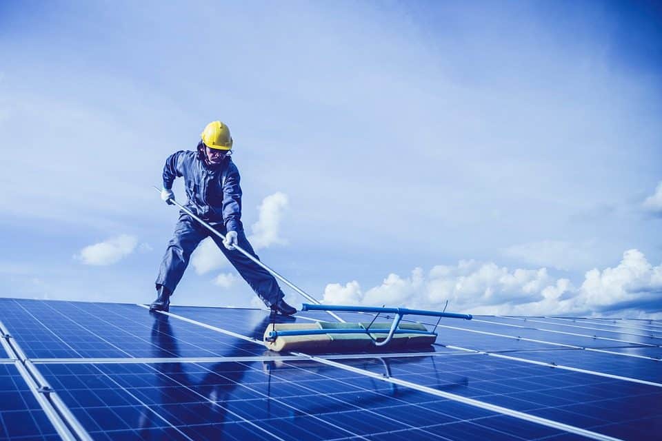 Technician cleaning rooftop solar panels