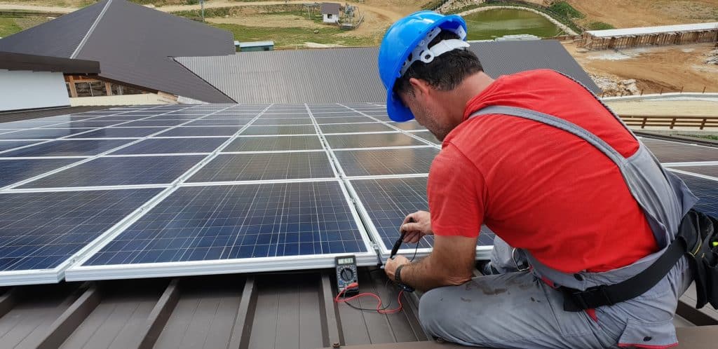 A photo of a man installing solar panels on a roof