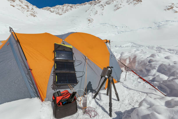 A climber has placed a solar panel charging system outside the tent to charge batteries for devices